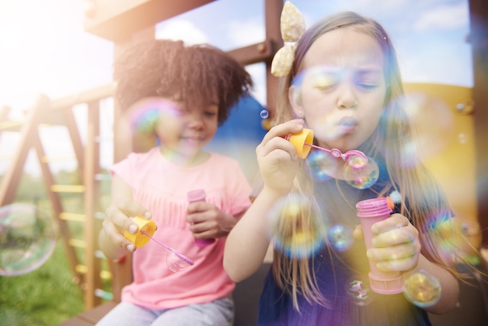 Two cute girls blowing the soap bubbles